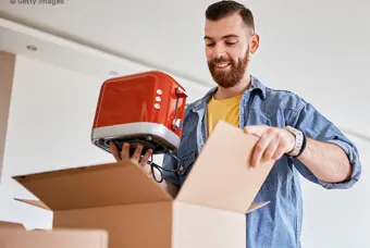 Un homme sort un grille-pain d'un carton de déménagement